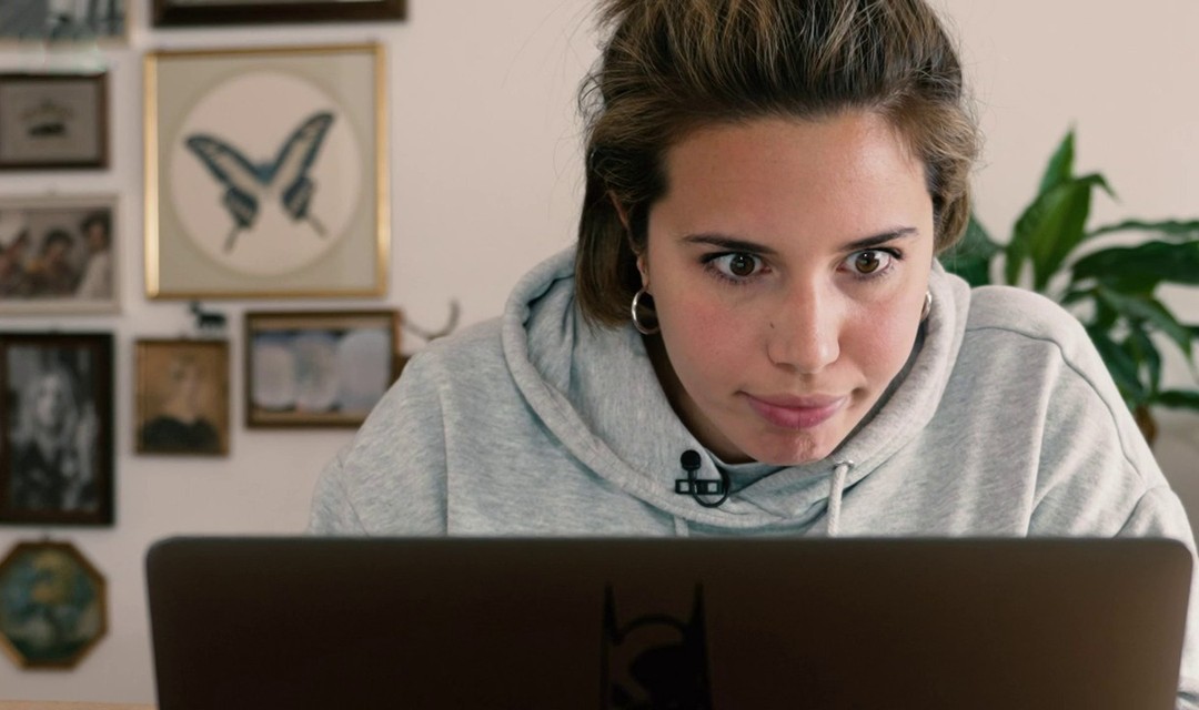 Host Jara Helmi sitzt mit starrem Blick hinter ihrem Laptop