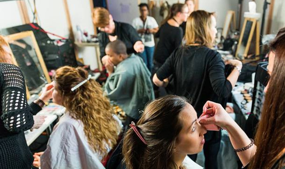 Eine Garderobe voller Menschen die Geschminkt werden oder am schminken sind.