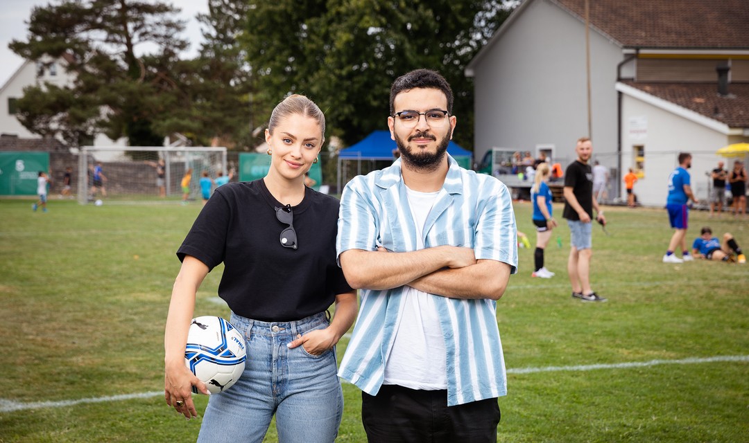 Die beiden Hosts Jennifer Bosshard (SRF) und Yacine Nemra (RTS) stehen auf einem Fussballplatz