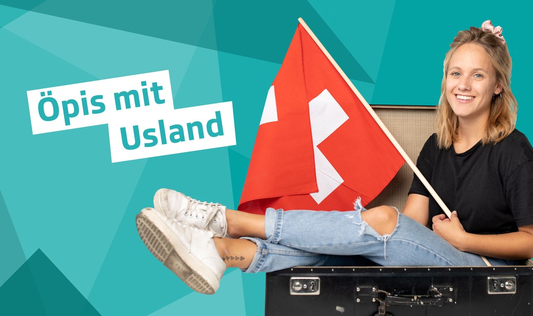 Eva sitzt mit einer Schweizer Fahne in der Hand in einem Reisekoffer