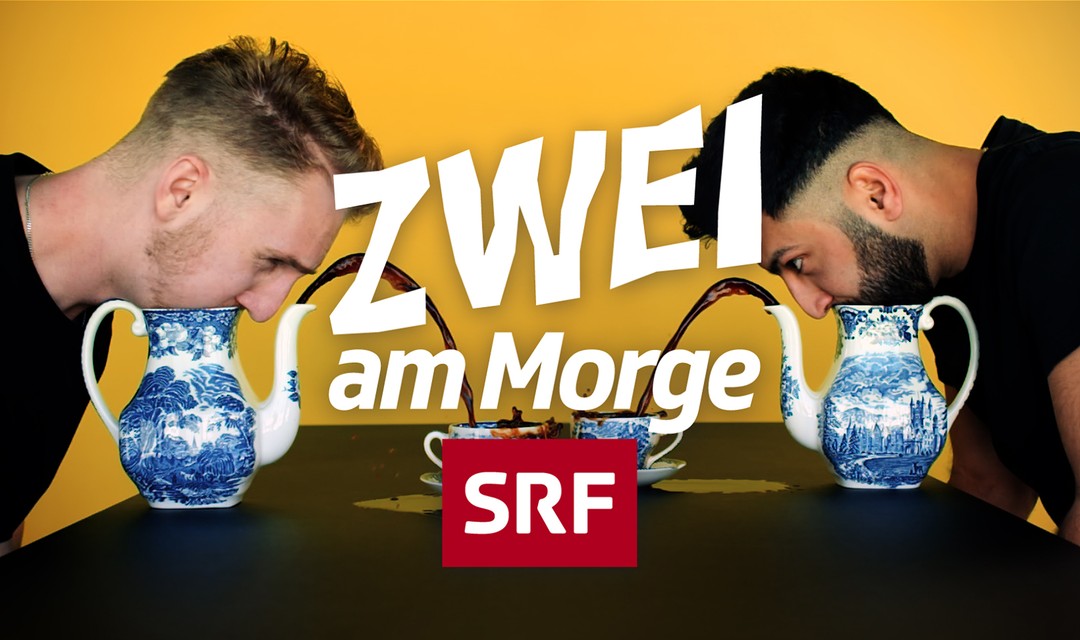 Julian und Ramin sitzen am Tisch und sind über ihre Kaffeetassen gebückt