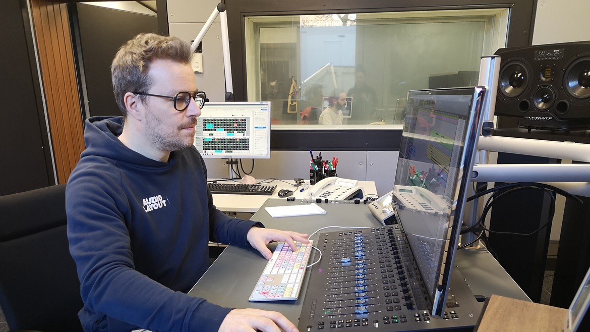 Sascha sitzt im Tonstudio am Bildschirm und bewegt mit der Maus die Audiopegel