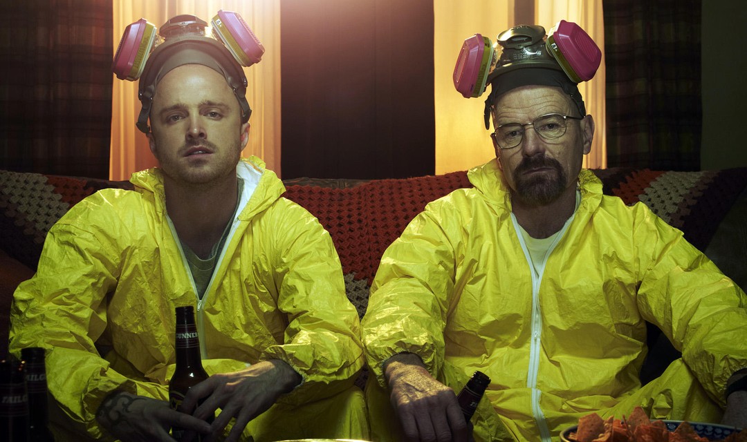 Schauspieler Aaron Paul und Bryan Cranston mit gelben Anzügen und Atem-Maske auf dem Kopf